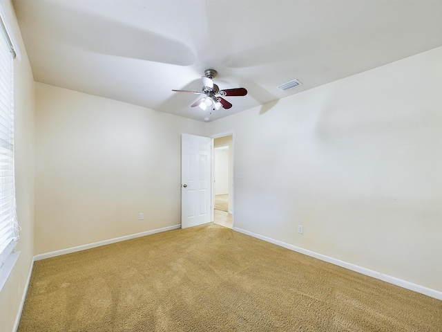 unfurnished room with carpet, visible vents, ceiling fan, and baseboards