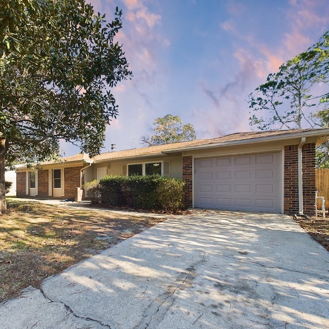 single story home with a garage, concrete driveway, and brick siding