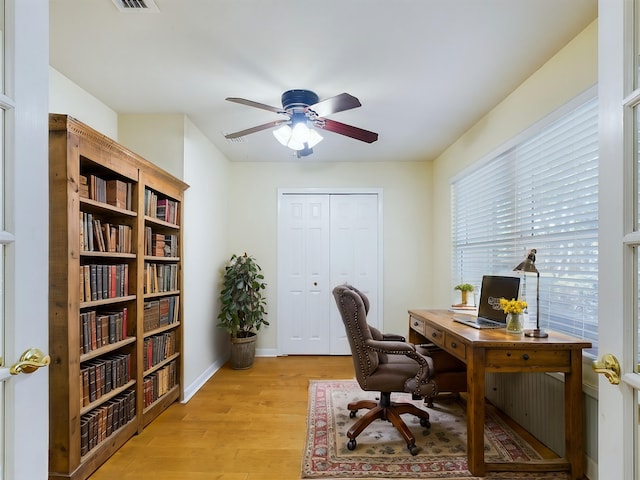 office area with ceiling fan, light wood finished floors, visible vents, and baseboards