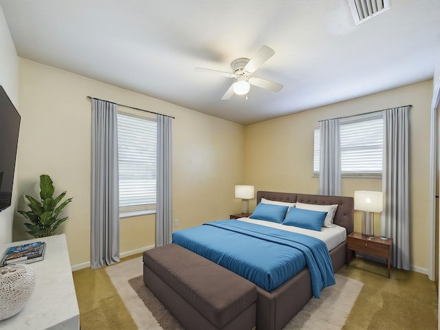 bedroom featuring baseboards, visible vents, ceiling fan, and light colored carpet