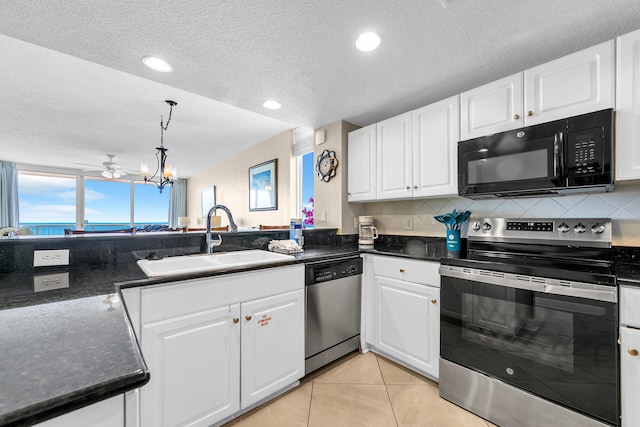 kitchen with sink, light tile patterned floors, appliances with stainless steel finishes, white cabinetry, and decorative light fixtures