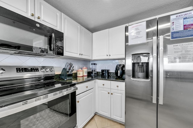 kitchen with appliances with stainless steel finishes, light tile patterned floors, white cabinets, and decorative backsplash