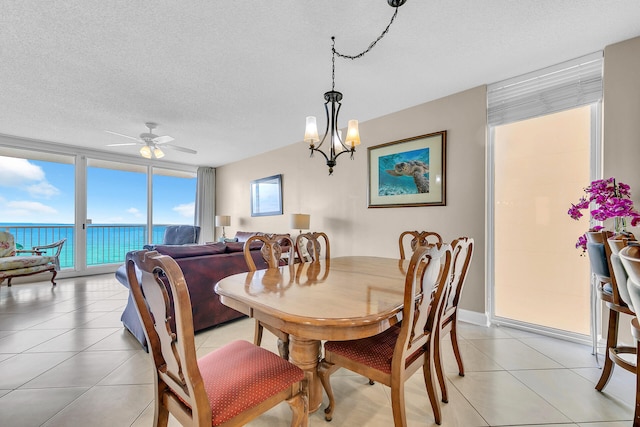 tiled dining room with expansive windows, ceiling fan, a water view, and a textured ceiling