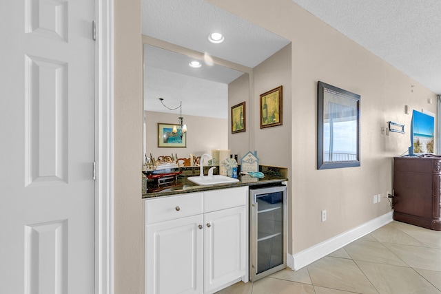 bathroom featuring vanity, beverage cooler, tile patterned flooring, and a textured ceiling