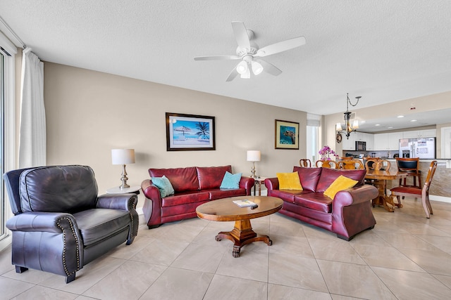 tiled living room with ceiling fan with notable chandelier and a textured ceiling