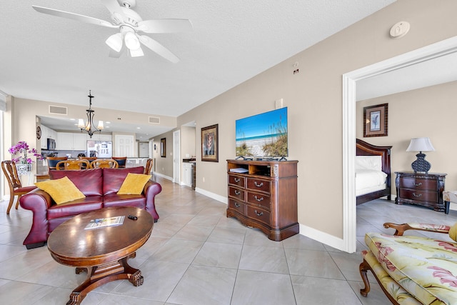 living room featuring ceiling fan with notable chandelier, a textured ceiling, and light tile patterned floors