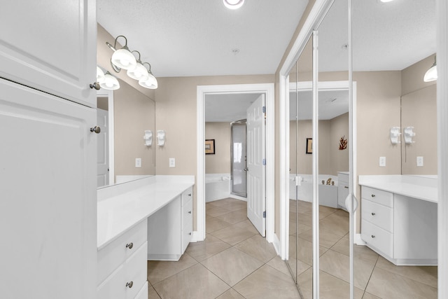 bathroom with tile patterned floors, vanity, a bathing tub, and a textured ceiling