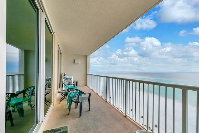 balcony featuring a view of the beach and a water view