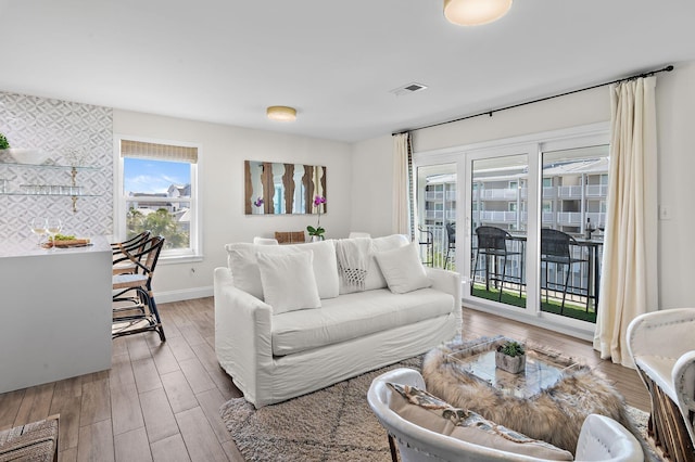 living area with visible vents, baseboards, and wood finished floors