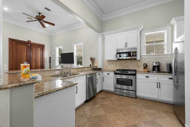 kitchen with sink, appliances with stainless steel finishes, white cabinets, decorative backsplash, and kitchen peninsula