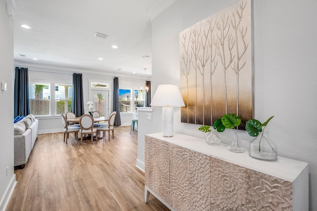 hall with ornamental molding and light hardwood / wood-style floors