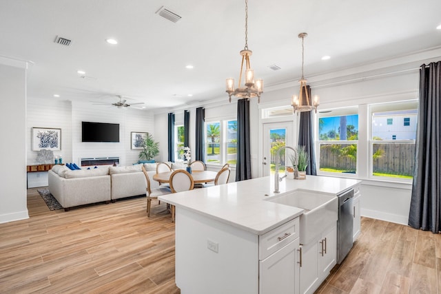 kitchen with pendant lighting, sink, white cabinets, a kitchen island with sink, and stainless steel dishwasher