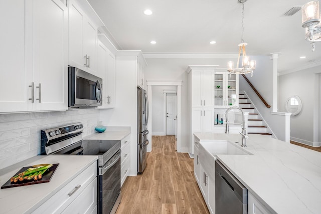 kitchen featuring white cabinetry, light stone countertops, decorative light fixtures, and stainless steel appliances