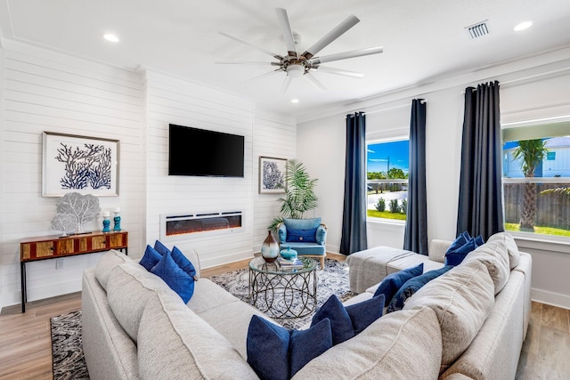 living room with crown molding, ceiling fan, a fireplace, and light hardwood / wood-style floors