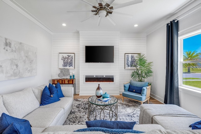 living room with crown molding, a large fireplace, hardwood / wood-style floors, and ceiling fan