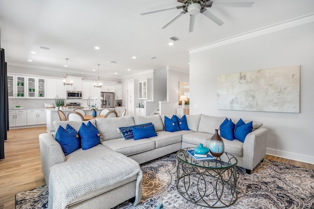 living room with sink, crown molding, light hardwood / wood-style floors, and ceiling fan