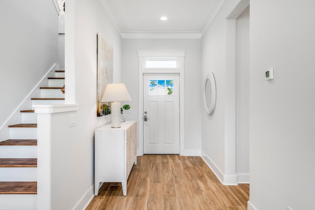 entryway with ornamental molding and light hardwood / wood-style floors