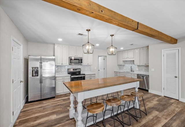 kitchen with dark wood-style floors, beam ceiling, stainless steel appliances, visible vents, and a sink