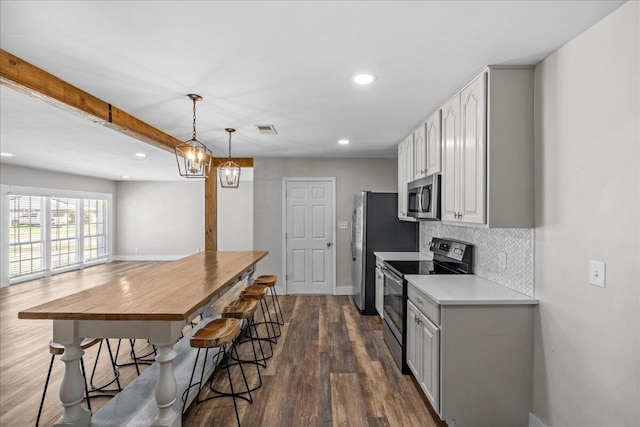 kitchen featuring visible vents, decorative backsplash, appliances with stainless steel finishes, dark wood-type flooring, and light countertops