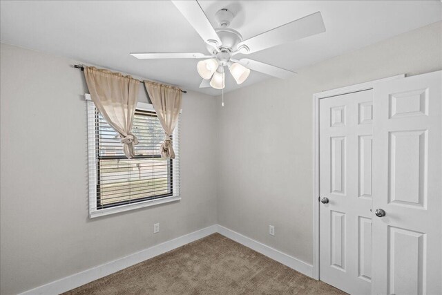 carpeted empty room with ceiling fan and baseboards