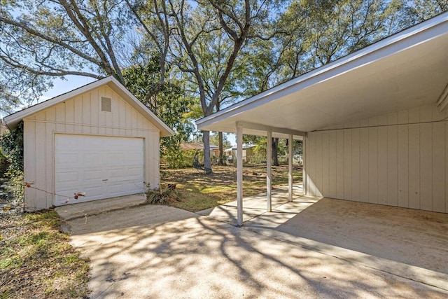 detached garage featuring concrete driveway and a carport