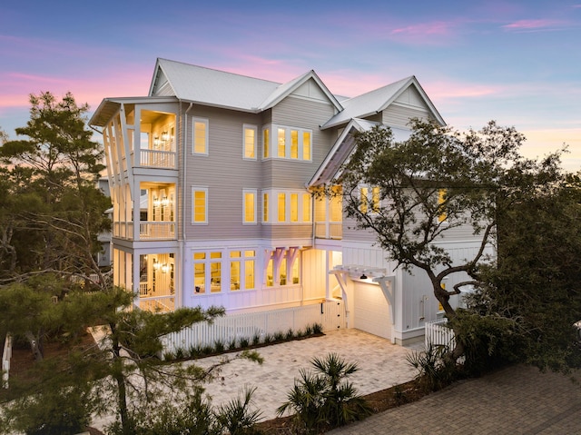 back house at dusk with a balcony and a garage