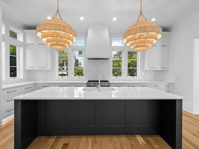 kitchen featuring a kitchen island with sink, white cabinetry, and custom exhaust hood