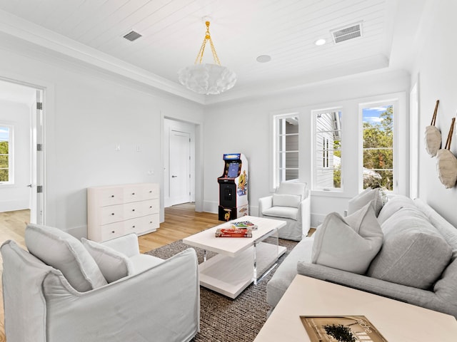 living room with light hardwood / wood-style flooring, wooden ceiling, ornamental molding, a tray ceiling, and a notable chandelier