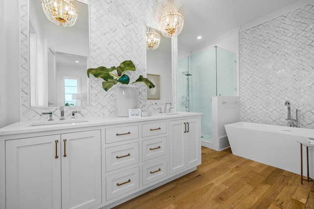 bathroom with plus walk in shower, hardwood / wood-style floors, vanity, crown molding, and an inviting chandelier