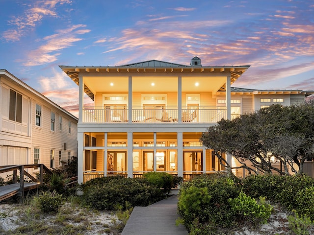 back house at dusk featuring a balcony