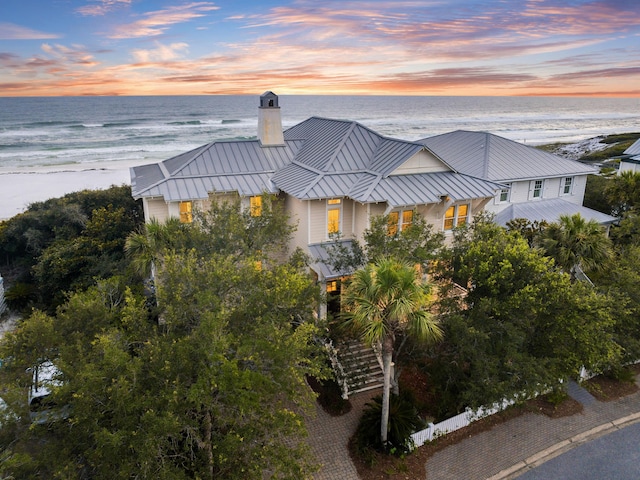 aerial view at dusk featuring a water view and a view of the beach