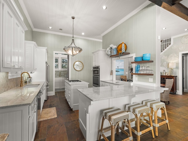 kitchen featuring white cabinetry, sink, light stone counters, and a kitchen island