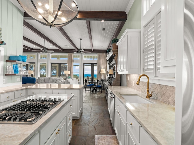 kitchen featuring sink, beam ceiling, stainless steel appliances, and hanging light fixtures