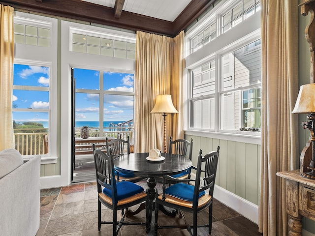 dining room featuring beamed ceiling and a water view