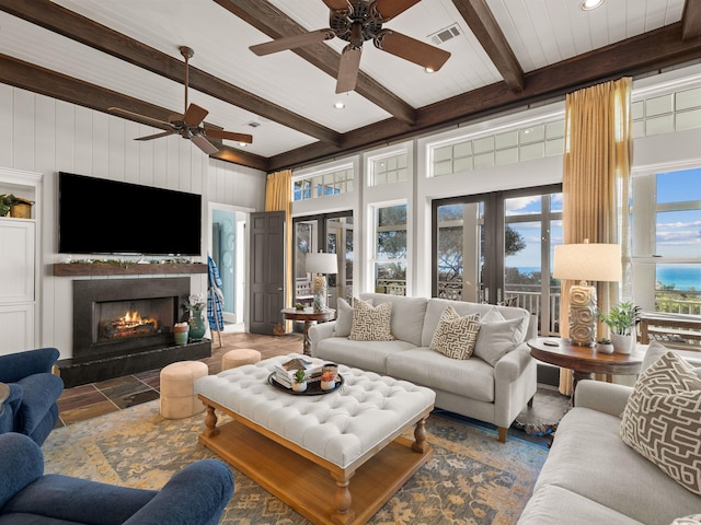 living room with ceiling fan, beamed ceiling, and wood walls