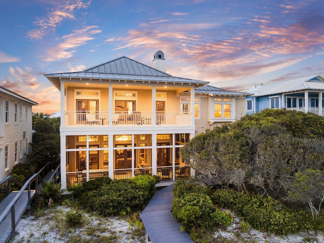 back house at dusk featuring a balcony