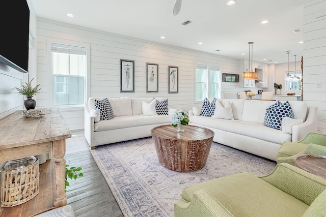 living room featuring light hardwood / wood-style flooring, wood walls, and plenty of natural light