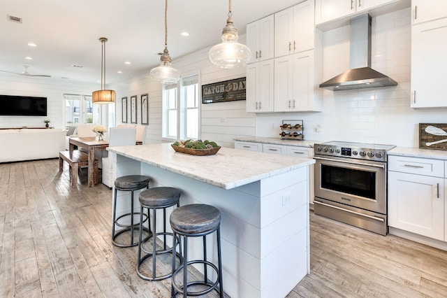 kitchen with white cabinetry, pendant lighting, wall chimney exhaust hood, and stainless steel electric range oven