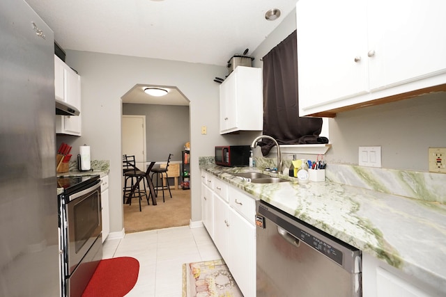 kitchen featuring sink, light tile patterned floors, appliances with stainless steel finishes, light stone counters, and white cabinets