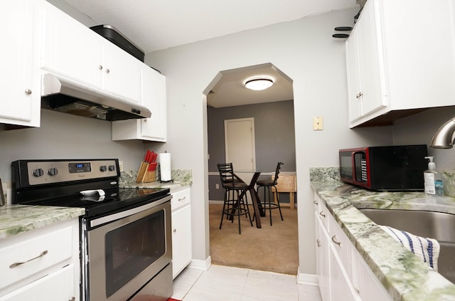 kitchen with stainless steel electric stove, sink, light carpet, and white cabinets