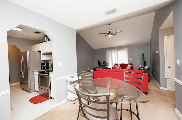 dining room with ceiling fan, lofted ceiling, and light carpet