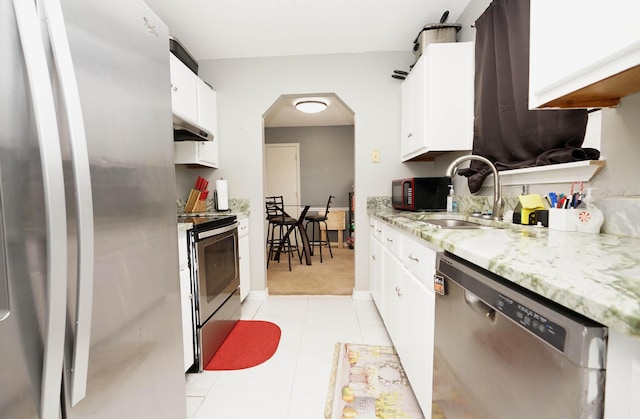 kitchen featuring sink, white cabinetry, stainless steel appliances, light stone counters, and light tile patterned flooring