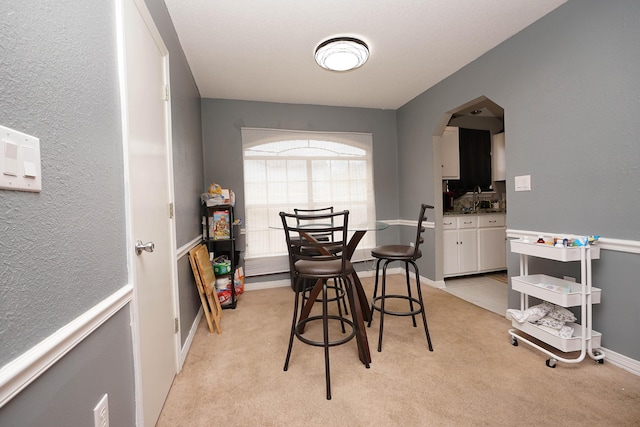 dining area with sink and light carpet