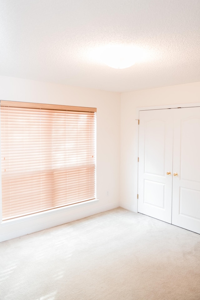 unfurnished room with carpet and a textured ceiling