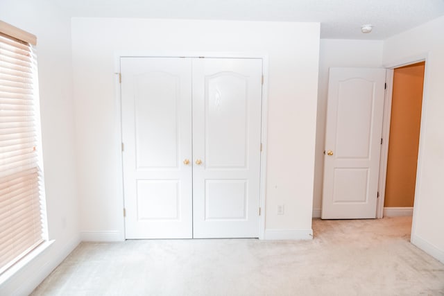 unfurnished bedroom with light carpet, a textured ceiling, and a closet