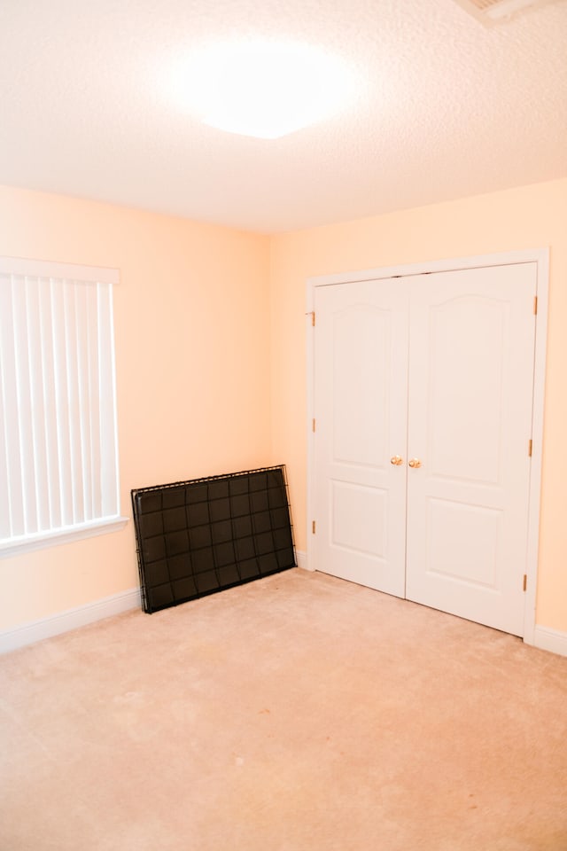 unfurnished bedroom with carpet flooring, a closet, and a textured ceiling