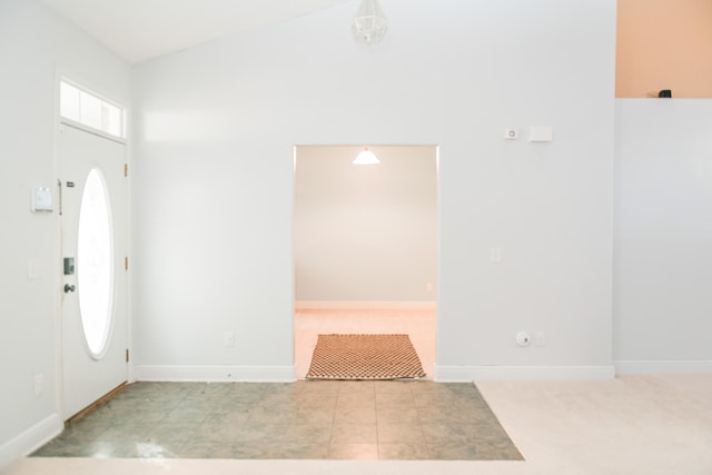 carpeted entrance foyer featuring high vaulted ceiling