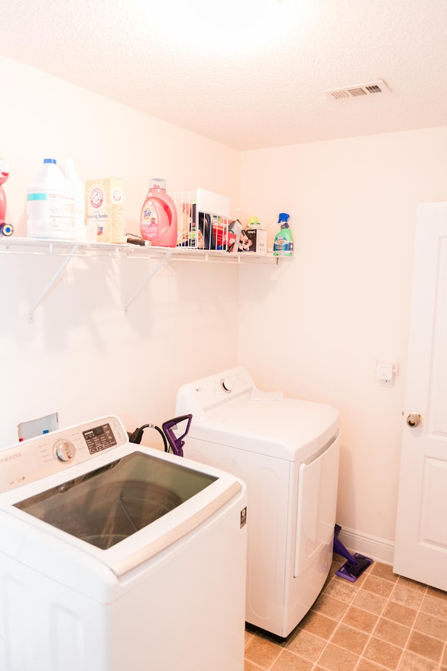 laundry area with independent washer and dryer, a textured ceiling, and light tile patterned flooring