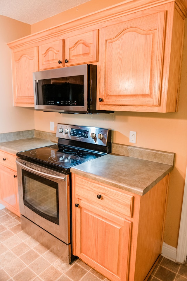 kitchen with light tile patterned floors, stainless steel appliances, and light brown cabinets