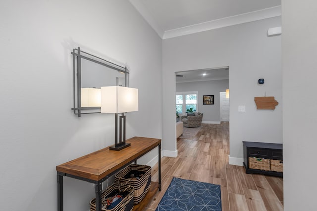 corridor featuring light wood-style floors, baseboards, and ornamental molding